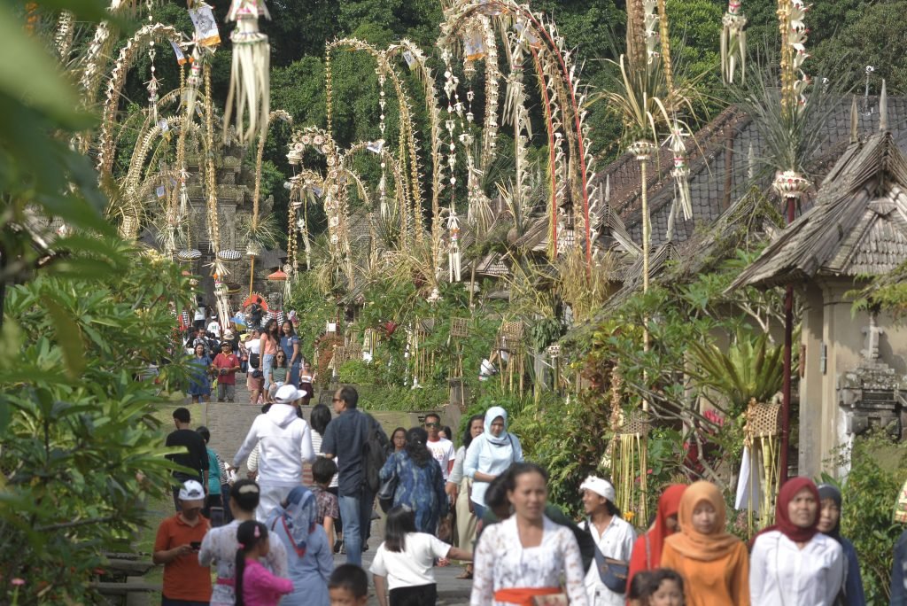 Wisatawan melintas di sekitar deretan rumah tradisional di Desa Wisata Penglipuran, Bangli, Bali, Rabu (26/12/2018).